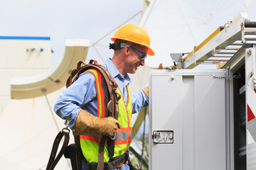Communications engineer getting equipment from truck with satellite antenna in background