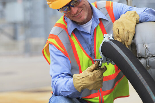 Electrical engineer inspecting hose connection for cooling supply lines at power plant