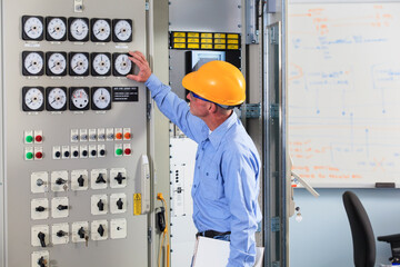 Electrical engineer inspecting power plant controls in central operations room of power plant