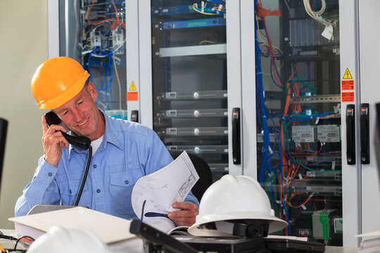 Electrical Engineer Reviewing Process Diagrams In Operations Room Of Electric Power Plant