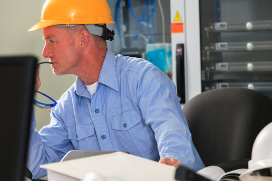 Electrical engineer studying monitor for performance in operations room of electric power plant