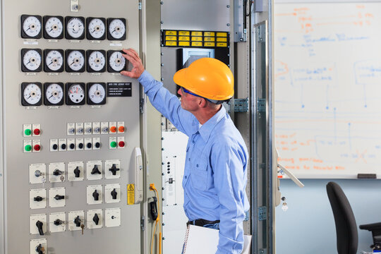 Electrical engineer inspecting power plant controls in central operations room of power plant
