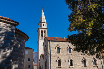 Fototapeta premium View of white Venetian bell tower in the medieval historic coastal town of Budva, Montenegro, Adriatic Mediterranean Sea, Montenegro, Balkan, Europe. Religious landmark on blue sky background