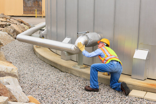 Engineer examining pipeline of water storage tank at electric power plant