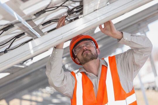Power engineer at solar photovoltaic array examining the connections of panels