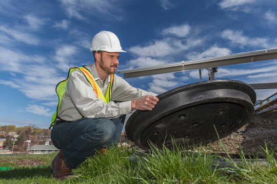 Power engineer opening inspection hatch at solar photovoltaic array