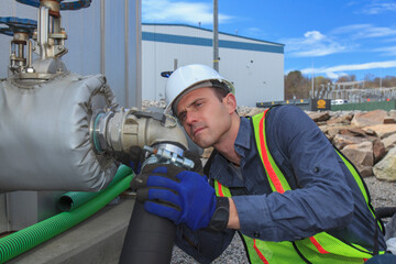 Industrial engineer examining hose connection at fuel tank at a power plant