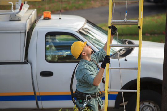Lineman placing ladder at power pole
