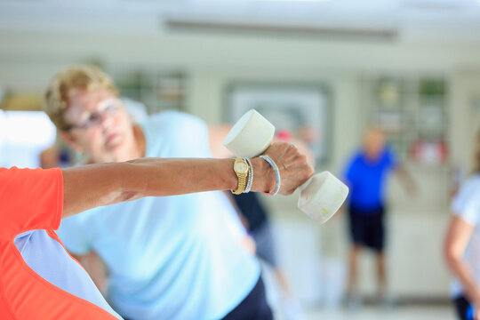 Female instructor lifting free weights in a senior's fitness class