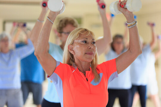 Female instructor lifting free weights in a senior's fitness class