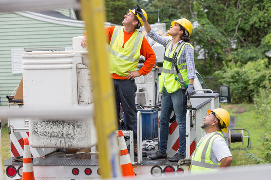 Utility workers looking at the line work in the rain
