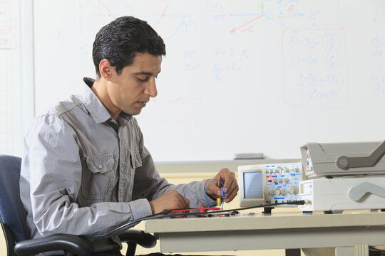 Engineering student inserting component into prototyping breadboard for an electronics lab experiment