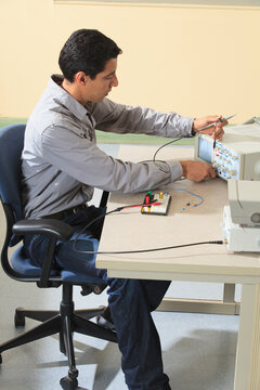 Engineering student adjusting oscilloscope to measure prototyping breadboard for an electronics lab experiment