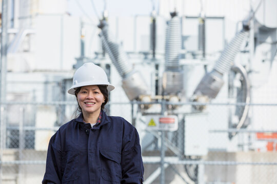 Portrait of female power engineer in front of high voltage transformer at power station
