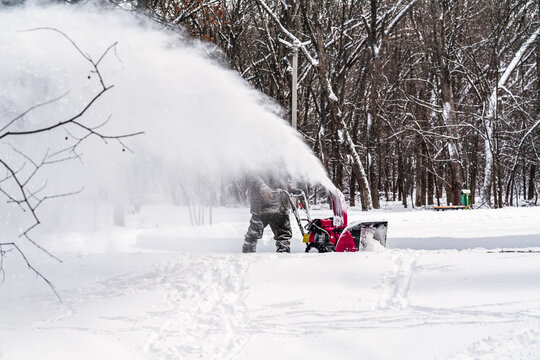 Men remove snow in the park with a snow blower