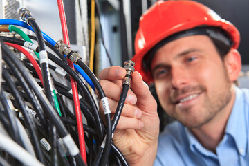 Network engineer holding BNC cable connection at patch panel