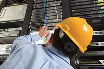 Network engineer installing cable equipment in rack