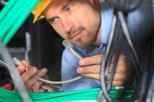 Network engineer examining patch cable under patch panel