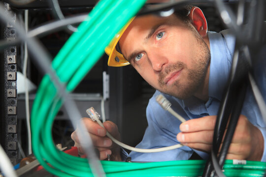 Network engineer examining patch cable under patch panel