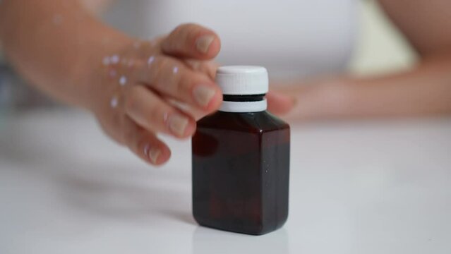 Male hand placing bottle with medication on table as female hand with monkey pox rash taking solution. Unrecognizable Caucasian patient with transmissible contagious disease consulting doctor