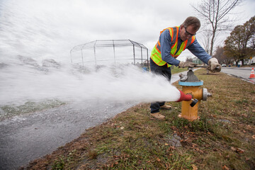 Water department technician opening fire hydrant to flush water pipes