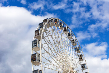 Ferris wheel on the background of the sky and white clouds