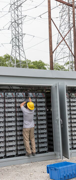 Engineer connecting energy storage batteries for back up power to an electric power plant