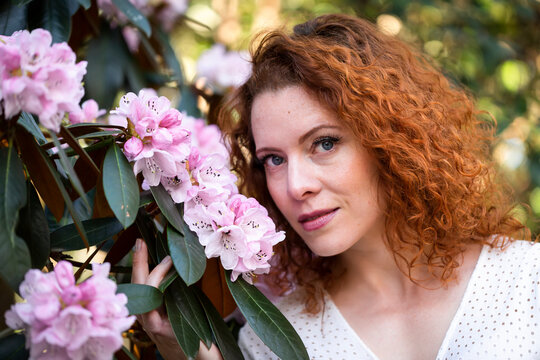Portrait of a woman with red hair among the cherry blossoms; Vancouver, British Columbia, Canada