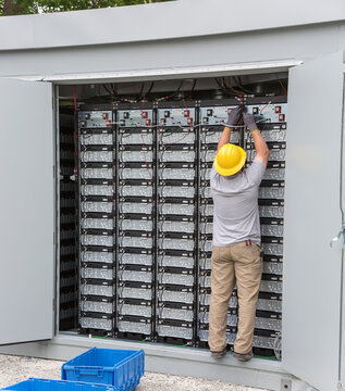 Engineer connecting energy storage batteries for back up power to an electric power plant