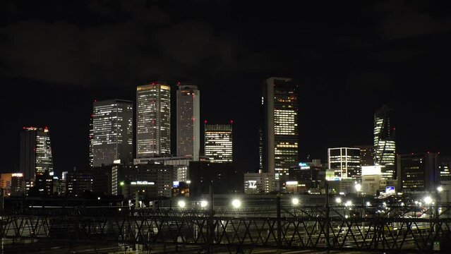 NAGOYA, JAPAN - OCTOBER 2022 : View of buildings around NAGOYA STATION and railroad at night from Koyabashi (bridge). Time lapse shot. Japanese business and transportation concept video.