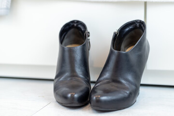 pair of black boots with high heels in front of a white closet