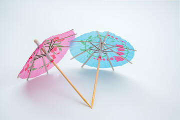 rear view of pink and light blue cocktail parasols with sticks isolated on a white background
