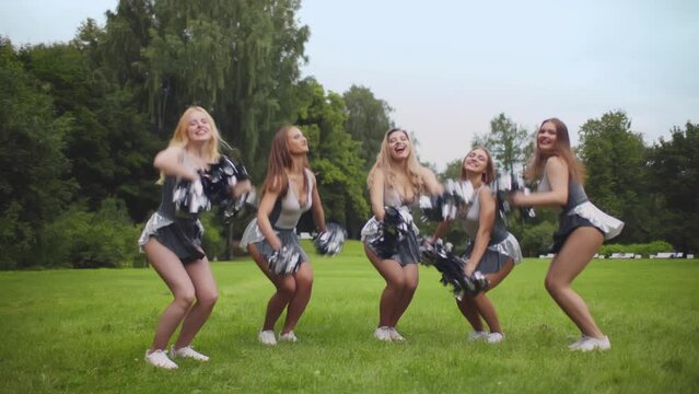 Cheerleader young girls team jump with pom poms during performance. Realtime