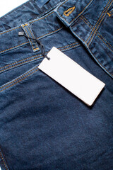 Mock-up of a white card of a clothing tag on denim trousers