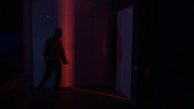 Man silhouette creeping about on tiptoe in the red light of opening door in dark room. mystery concept. Crime, evil and horror concept.