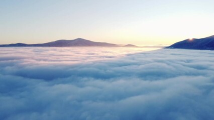 Sun coming up from behind the snow-covered mountains illuminates the sea of clouds and the mountain slopes rising out of the mist with its orange-pink glow. Moravskoslezsky region, Czech republic - Powered by Adobe