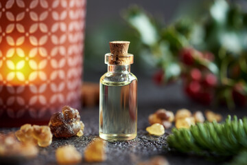 Obraz na płótnie Canvas Christmas essential oil with frankincense resin, fir, holly and a candle
