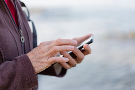 Close-up detail of a woman's hands using a smart phone while hiking; British Columbia, Canada
