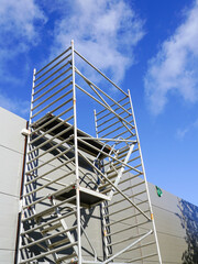 Modern metal tubular multilevel scaffolding next to the sandwich panel facade