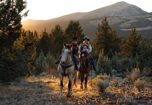 Wild mustang trainer horseback rides with her children; Prineville, Oregon, United States of America