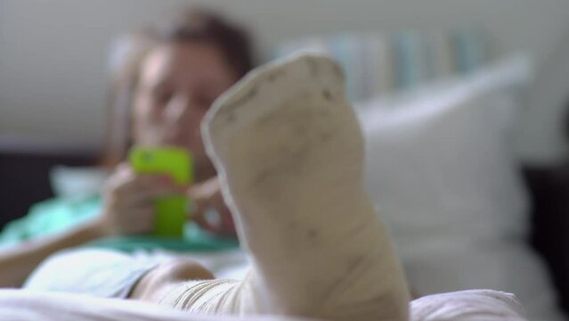 Young woman with foot bone fracture resting on couch at home after a foot injury accident