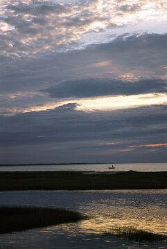 Sunset on salt marsh with man in a boat.; Yarmouth, Cape Cod, Massachusetts.