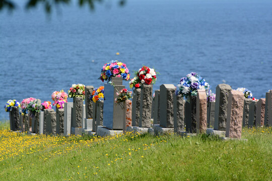 Grave stones with bouquets in a seaside Catholic cemetery on the Gaspesie.; Parc de la Gaspesie, Quebec, Canada.