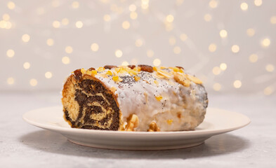 Christmas Polish strudel Makowiec with poppy seeds,traditional polish festive cake covered with sugar icing, walnuts, dried fruits on white background with lightening. Horizontal. Winter holiday.