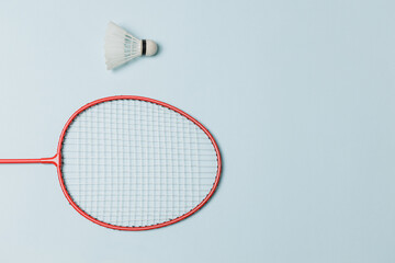 Single badminton racket and shuttlecock isolated on light blue colored background for psychology or...