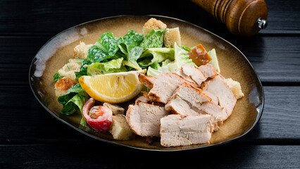 Caesar salad with chicken and greens on wooden table