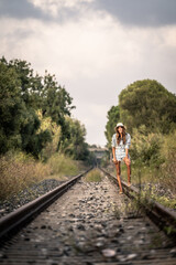Fototapeta na wymiar woman in cowboy dress walking on a railway