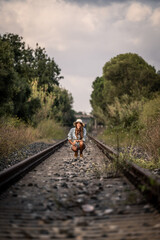 woman in cowboy dress walking on a railway
