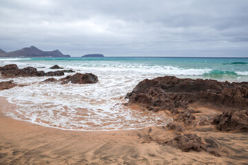 Coastal landscape with wet rocks and shore water on the beach