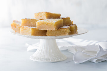 Sweet and tangy lemon bars on a white pedestal stand.